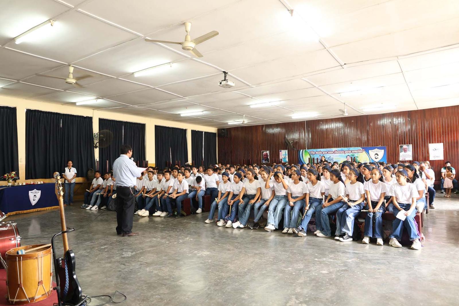 Estudiantes reunidos con un docente en el salón de actos del colegio